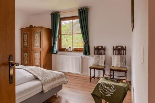 een slaapkamer met 2 stoelen, een bed en een raam bij Ritterhof Apartments in Rauris