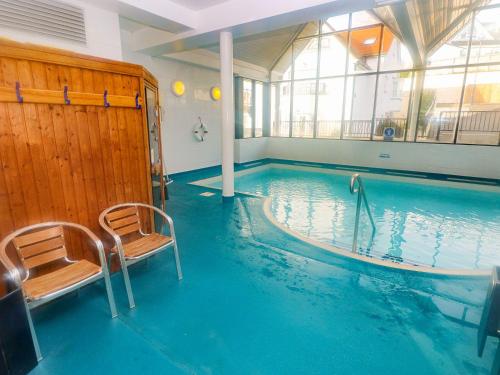 a swimming pool with two chairs in a building at Seashells in Tenby