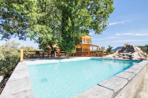 ein Schwimmbad mit einem Haus im Hintergrund in der Unterkunft Romantic Tree House in Kato Pavliana