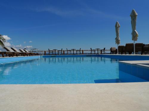 a large blue swimming pool with chairs and umbrellas at Barbagiannis House in Ormos Panagias