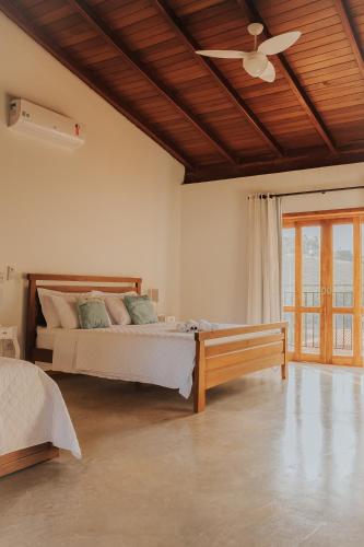 a bedroom with a bed and a ceiling fan at Pousada Cheiro da Terra - Sem Café da Manha in Capitólio