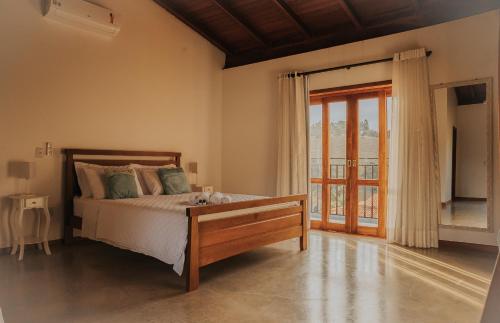 um quarto com uma cama e uma grande janela em Pousada Cheiro da Terra em Capitólio