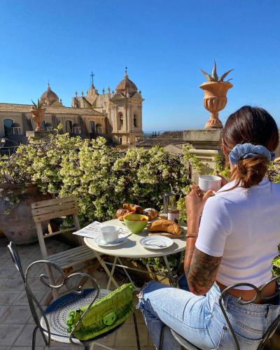 a woman sitting at a table with a plate of food at Casa Modica - Luxury rooms in Noto