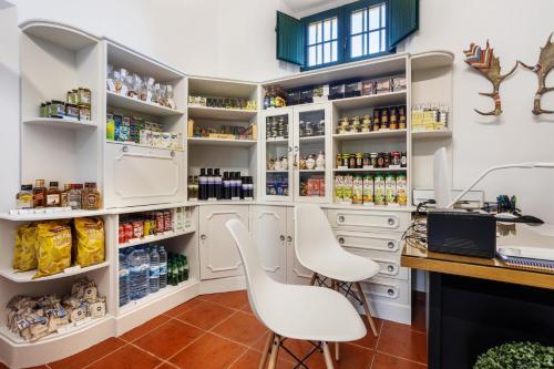 a kitchen with white cabinets and white chairs at QSF Agro Turismo Quinta da Sagrada Família in Évora