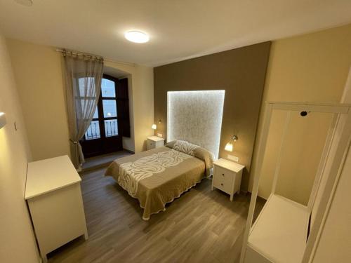 a small bedroom with a bed and a window at Apartamentos Sol del Prior in Úbeda