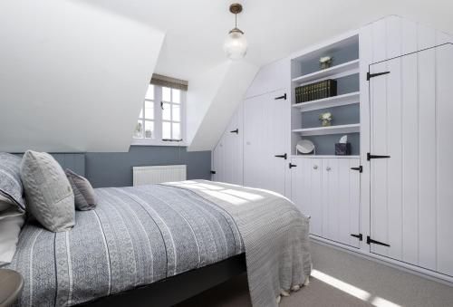 a bedroom with a bed and a white cabinet at Old Stable Cottage in Kingham