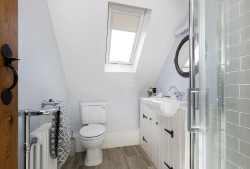 a white bathroom with a toilet and a sink at Old Stable Cottage in Kingham
