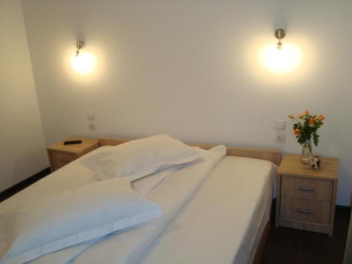 a bedroom with a bed with white sheets and two lights at Casa cu Flori in Buşteni
