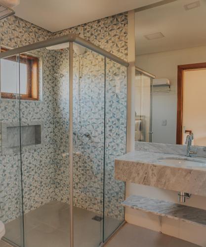 a bathroom with a glass shower and a sink at Pousada Cheiro da Terra - Sem Café da Manha in Capitólio