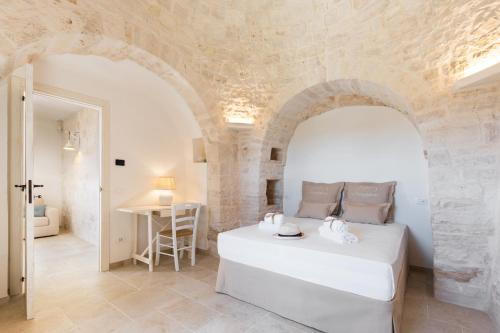 a bedroom with a white bed in a stone wall at Mandolario Trulli Resort in Martina Franca