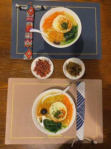 a table with two plates of food and bowls of food at 丽江束河元年别院 Yuannian Lijiang in Lijiang