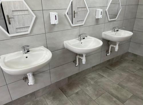 a bathroom with two sinks and mirrors on the wall at POLICYJNY OŚRODEK WYPOCZYNKOWY in Niesulice
