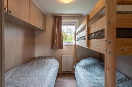 ein kleines Schlafzimmer mit 2 Etagenbetten und einem Fenster in der Unterkunft Luxe 5-persoons chalet op familiecamping in Baarland