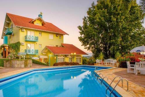uma casa com piscina em frente a uma casa em Hotel Pousada da Neve em Nova Petrópolis