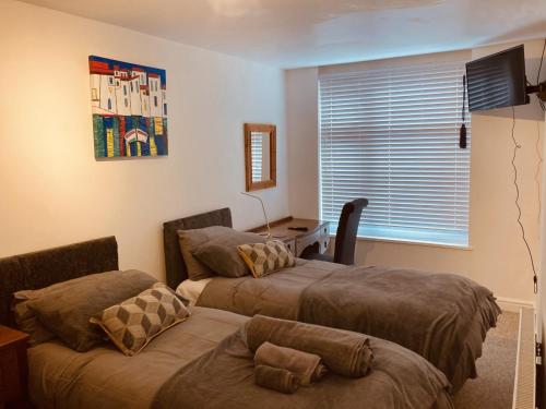a bedroom with two beds and a window and a table at 3 Entire Stunning & Cosy Apartments in same property, 4 Double Bedrooms, 3 Bathrooms, 3 Kitchens, Terrace in Kidderminster