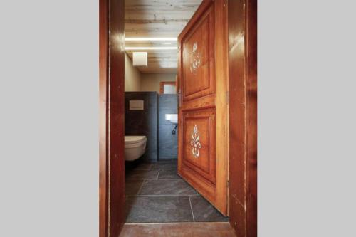 a bathroom with a toilet and a wooden door at Chalet Sonnblick in Stuben am Arlberg