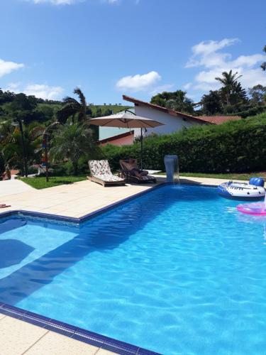 a large blue swimming pool next to a house at Chácara Santa Rita in Bom Jesus dos Perdões