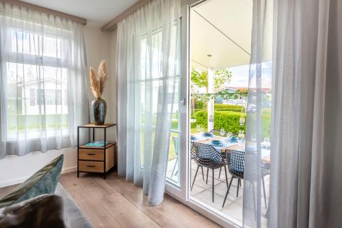a room with a glass door with a table and chairs at Luxe 5-persoons chalet op familiecamping in Baarland