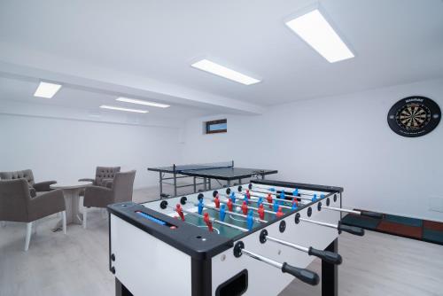 a foosball table in a room with chairs and a clock at Błękitne Wzgórze - Nowoczesne Pokoje Gościnne in Władysławowo