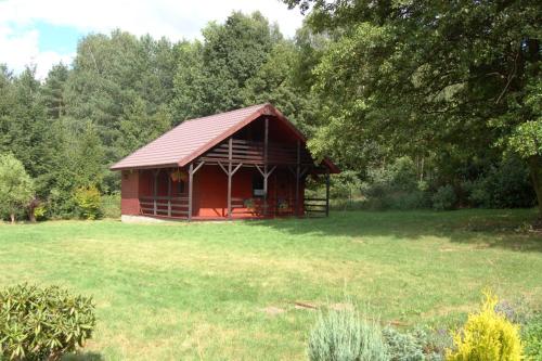 a small red cabin in a field of grass at Domek Zofiówka dostęp na kod in Zofiówka