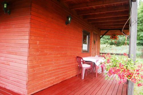 a red deck with a table and chairs on it at Domek Zofiówka dostęp na kod in Zofiówka