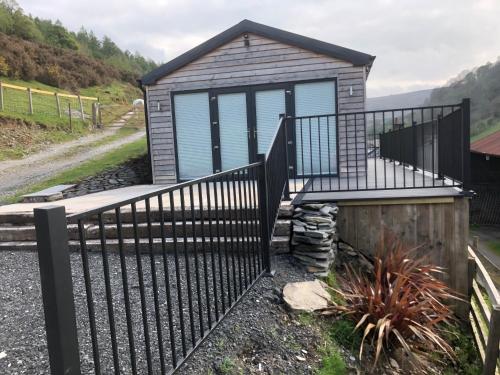 a tiny house with a deck and a gate at The Lodge in Llangollen