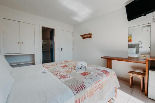 a bedroom with a bed and a table and a kitchen at Calador Búzios Hotel in Búzios