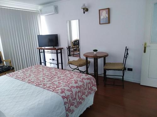 1 dormitorio con 1 cama, mesa y sillas en RoomApart Escuela Militar, en Santiago