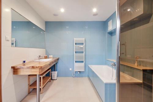 y baño con paredes azules, lavabo y bañera. en Apartamenty Turystyczna Małgorzata, en Międzyzdroje
