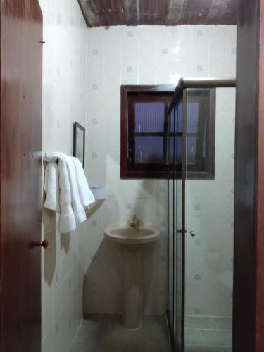 a bathroom with a toilet and a shower and towels at Pousada da Barra in Barra de São João