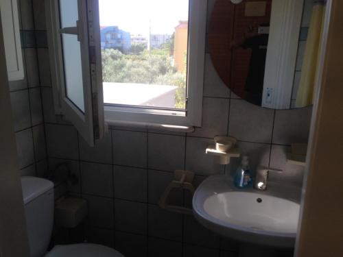a bathroom with a sink and a mirror and a window at House with Garden in Nea Peramos