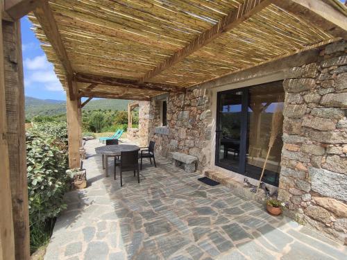 ein Steinhaus mit einer Terrasse mit einem Tisch in der Unterkunft Casa Lysandra in Serra-di-Ferro