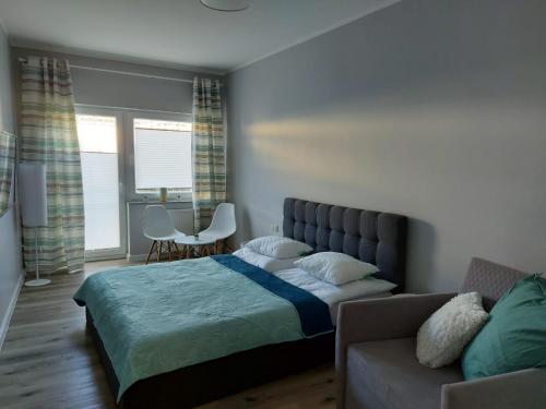a bedroom with a bed and a couch at Apartamenty z tarasami "Miętowy spokój 15" "Romantyczna szarość 16" "Niebieska elegancja 17" maksymalnie dla 6 osób in Pobierowo