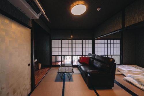 a living room with a leather couch and a bed at Hikari no mori-INN - Vacation STAY 10901 in Kumamoto