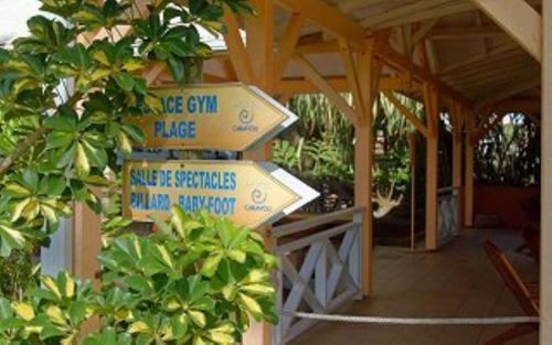 a group of signs on a building with trees at Studio La Valentina face à la marina in Les Trois-Îlets