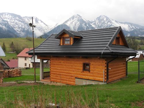 a house with a black roof with mountains in the background at Chatka Zornica in Ždiar