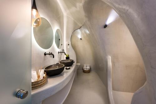 a bathroom with two sinks and two mirrors at Deep in cave suites in Fira