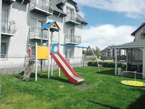 un parque infantil frente a un edificio de apartamentos con un tobogán en Solar Bed & Breakfast, en Karwia