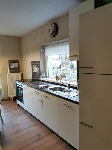 a kitchen with white cabinets and a sink and a window at Gästehaus Vergissmeinnicht in Guteborn