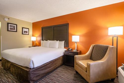 a hotel room with a large bed and a chair at Clarion Inn Biltmore Village in Asheville