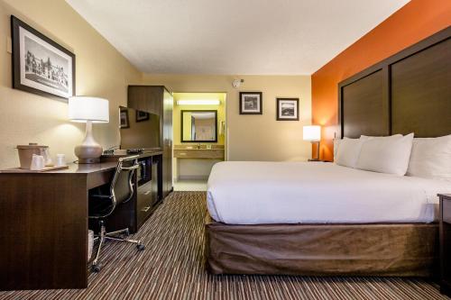 a hotel room with a large bed and a desk at Clarion Inn Biltmore Village in Asheville