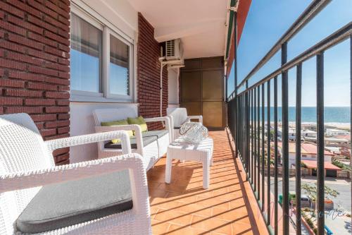 a balcony with white chairs and a view of the ocean at Tres dormitorios ,vistas al mar , junto a la playa in Punta Umbría