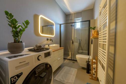 een wasmachine in een badkamer met een douche bij Karamba boutique living - ECO Riverside Appartment in Volos