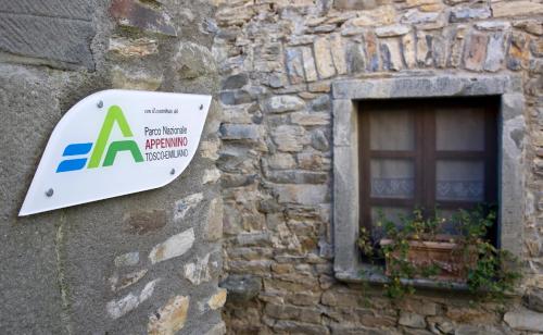 a sign on the side of a stone building with a window at Agriturismo Montagna Verde Apella in Licciana Nardi