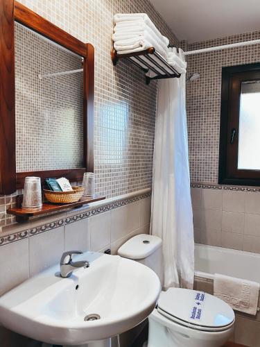 ein Badezimmer mit Waschbecken, Toilette und Spiegel in der Unterkunft Hotel Valdevécar in Albarracín