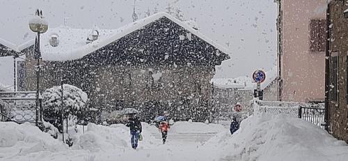 two people walking down a street in the snow at B&B SognoInCadore in Domegge di Cadore