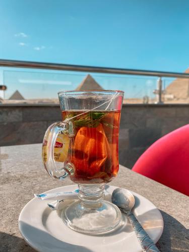a glass cup of tea on a plate with a spoon at Best View Pyramids Hotel in Cairo