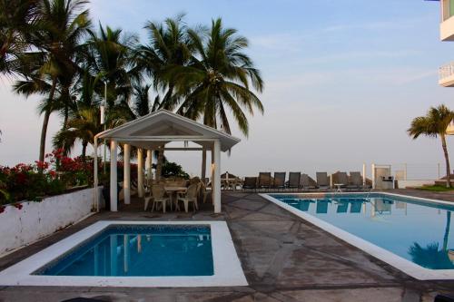a swimming pool with a gazebo next to a resort at Hotel y Suites Corita in Bucerías
