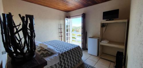 1 dormitorio con 1 cama y balcón con TV en Betume, en Campos do Jordão