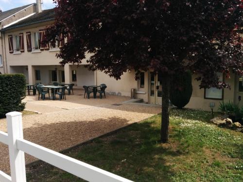 une clôture blanche devant une maison avec un arbre dans l'établissement Relais Henri IV, à La Flèche